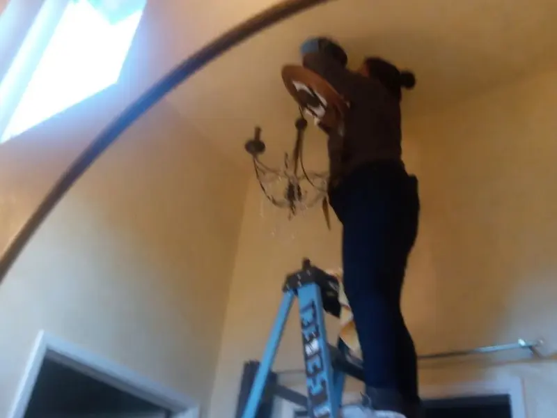 Electrician installing a chandelier in a Artesia residence